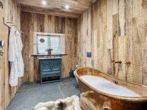 a wooden bathroom with a tub and a sink at Buttercup Cottage in Treborough +9 photos