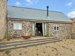 a stone house with a porch and a patio at Buttercup Cottage in Treborough