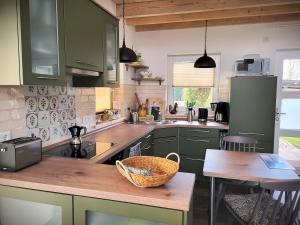 a kitchen with green cabinets and a basket on a table at Haus Theda in Fockbek