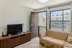 a living room with a couch and a flat screen tv at Casas em condomínio a Beira-Mar com piscina, Itajubá - MCSs in Itajubá