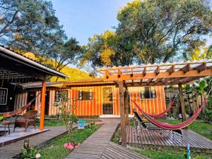 an orange tiny house with a hammock in the yard at Pousada Recanto das Cores in Ilha do Mel