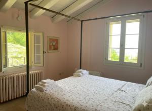 a bedroom with a bed with white sheets and windows at Casale IL SAMBUCO sui colli bolognesi in San Lazzaro di Savena