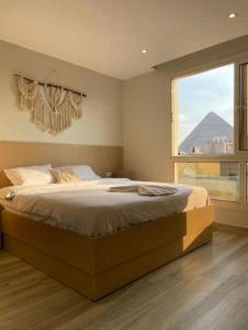 een slaapkamer met een groot bed en een groot raam bij Lumora Pyramids InN in Caïro