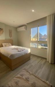 een slaapkamer met een bed en een groot raam bij Lumora Pyramids InN in Caïro