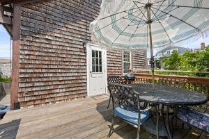 een houten terras met een tafel en een parasol bij Magnolia Portside Spacious 3BR on Thames St in Newport