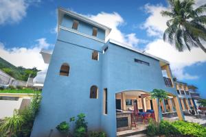 ein blaues Gebäude mit einer Palme davor in der Unterkunft Brisa Bliss in San Juan de Alima