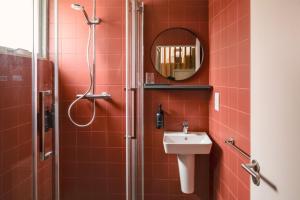 ein rot gefliestes Badezimmer mit Dusche und Waschbecken in der Unterkunft Modern Chatham home with garden retreat in Chatham