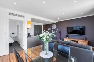 a living room with a vase of flowers on a glass table at Adelaide Central Skyline Panoramic Suite Two in Adelaide
