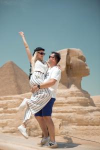 um homem e uma mulher de pé em frente às pirâmides em Lumora Pyramids InN em Cairo