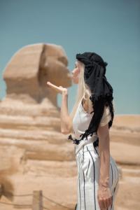 uma mulher em pé em frente a uma rocha em Lumora Pyramids InN em Cairo