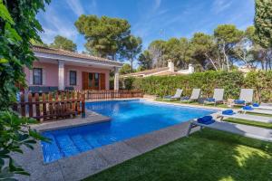 una piscina con sedie e una casa di Villa Damar a Can Picafort