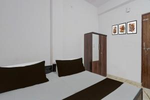 a bedroom with a bed with white sheets and black pillows at Hotel O Shri Panchmukhi Residency Baran Road in Kota