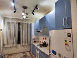 een keuken met blauwe kasten en een witte koelkast bij Gold 99 in Samarkand