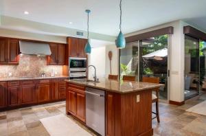 une cuisine avec des armoires en bois et des appareils en acier inoxydable dans l'établissement Spacious Island Home with Beach Access, à Waikoloa