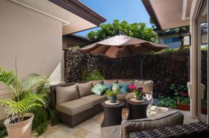 une terrasse avec un canapé et un parasol dans l'établissement Spacious Island Home with Beach Access, à Waikoloa