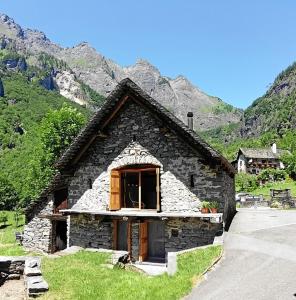una piccola casa di pietra con una finestra su una montagna di Stalla di Adele a Cevio