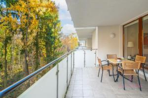 einen Balkon mit einem Tisch, Stühlen und Bäumen in der Unterkunft Your Holidays Aquamarina in Misdroy