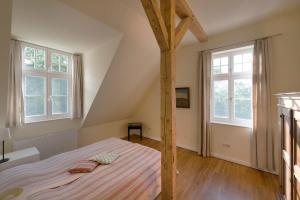a bedroom with a bed and two windows at Wohnung Im Zweiten Obergeschoss Des Gutshauses in Neuenkirchen