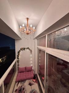 诺伊达Paris Style Luxe Apartment In The Heart Of Noida的客厅里有一盏枝形吊灯，旁边放着一把粉色椅子。