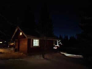 eine Blockhütte in der Nacht mit einem Fenster in der Unterkunft Lapland Aurora Riverside in Raiskio