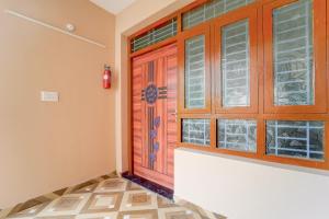 Habitación con puerta y ventanas de madera. en Collection O MKU Madurai Formerly Mpl Elite, en Samayanallūr