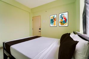 Un dormitorio con una cama con dos cuadros en la pared. en Collection O MKU Madurai Formerly Mpl Elite, en Samayanallūr