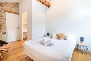 ein weißes Bett in einem Zimmer mit Ziegelwand in der Unterkunft Maison du Château, spacieuse et charmante près du PuyDuFou in Mortagne-sur-Sèvre