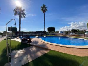 a swimming pool with palm trees in a resort at Casa Kessing in Orihuela Costa