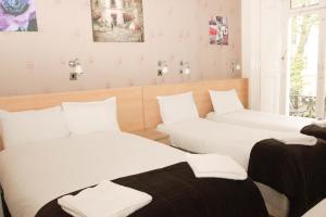 duas camas num quarto com lençóis brancos em Tony's House Hotel em Londres