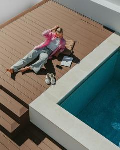 a woman sitting on a deck next to a swimming pool at Outsite Sagres - Work, Connect, Explore in Sagres