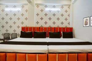 a bedroom with a large bed with orange accents at Hotel O Sri in Banāras Cantonment
