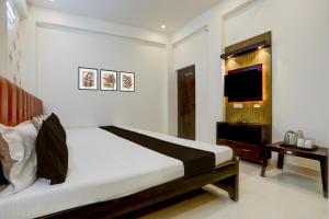a bedroom with a large bed and a television at Hotel O Sri in Banāras Cantonment