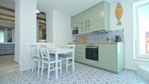 una cucina con mobili verdi, tavolo e sedie di Casa Bianca a Skopelos Town