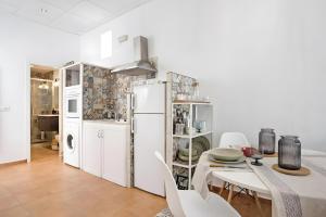 a white kitchen with a table and a white refrigerator at Charming Andalusian Loft in Vejer de la Frontera
