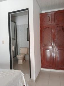 a bathroom with a toilet and a wooden door at Hotel Unión in Villavicencio