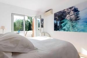 a bedroom with a white bed with a painting on the wall at Beautiful Sea View Villa Minerva in Sant Josep +35 photos