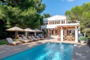 a pool with chairs and umbrellas next to a house at Beautiful Sea View Villa Minerva in Sant Josep