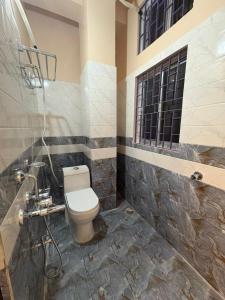 a bathroom with a toilet and a window at Hotel Maple Lawn in Guwahati