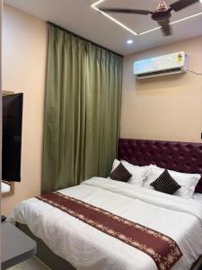 a bedroom with a bed and a television on the wall at Hotel Maple Lawn in Guwahati +18 photos
