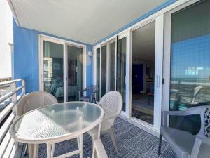 a patio with a glass table and chairs on a balcony at Atlantic Dunes - 101 in Myrtle Beach