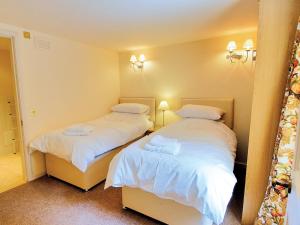 ein Schlafzimmer mit zwei Betten mit weißer Bettwäsche in der Unterkunft Courtyard Cottage in Smailholm