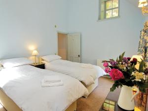 2 Betten in einem Zimmer mit einer Blumenvase in der Unterkunft Courtyard Cottage in Smailholm