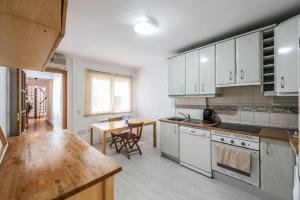 une cuisine avec des armoires blanches et une table en bois dans l'établissement ARCO Gran Via Boutique Apartments, à Madrid