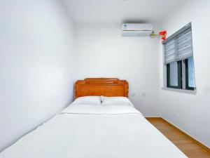 a white bed in a room with a window at Nearby Time in Beihai