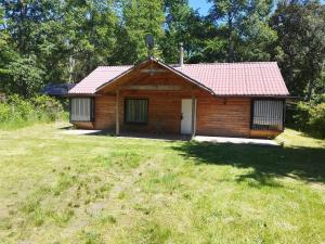 a small wooden cabin with a grassy yard at Pucón, casa en parcela in Pucón