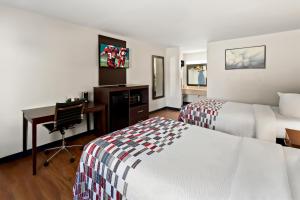 a hotel room with two beds and a desk at Red Roof Inn Muscle Shoals in Muscle Shoals +38 photos