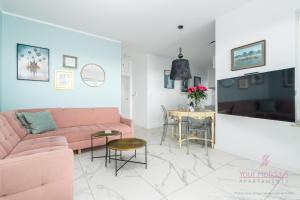 ein Wohnzimmer mit einem rosa Sofa und einem Tisch in der Unterkunft Your Holidays Aquamarina Onyx 98 in Misdroy + 7 Fotos