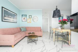 ein Wohnzimmer mit einem rosa Sofa und einem Tisch in der Unterkunft Your Holidays Aquamarina Onyx 98 in Misdroy