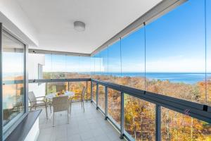 einen Balkon mit Glaswänden sowie einem Tisch und Stühlen in der Unterkunft Your Holidays Aquamarina Onyx 98 in Misdroy