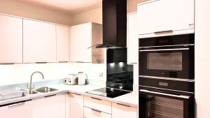 a kitchen with white cabinets and black appliances at Free Parking Heart of Bristol City Stay in Bristol +4 photos